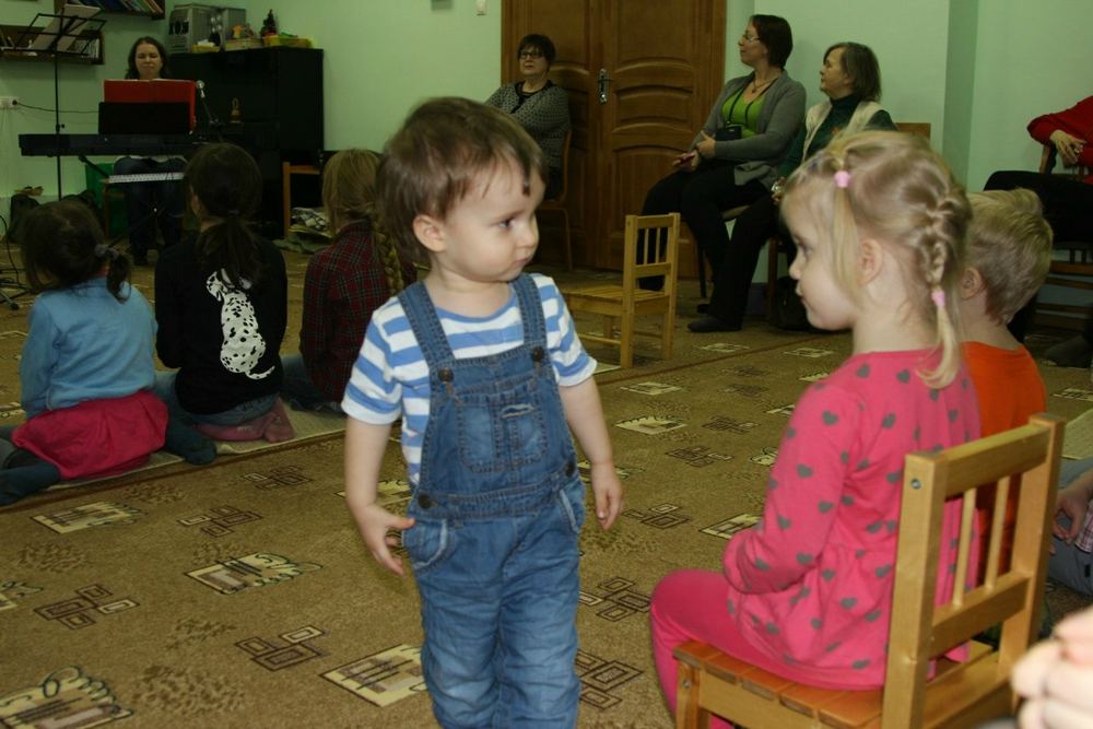 Двое малышей танцуют посреди зала во время концерта.